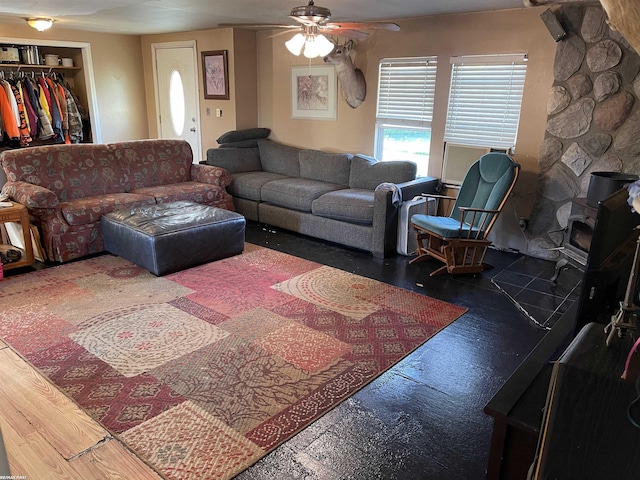 living room with dark hardwood / wood-style flooring, a wood stove, and ceiling fan