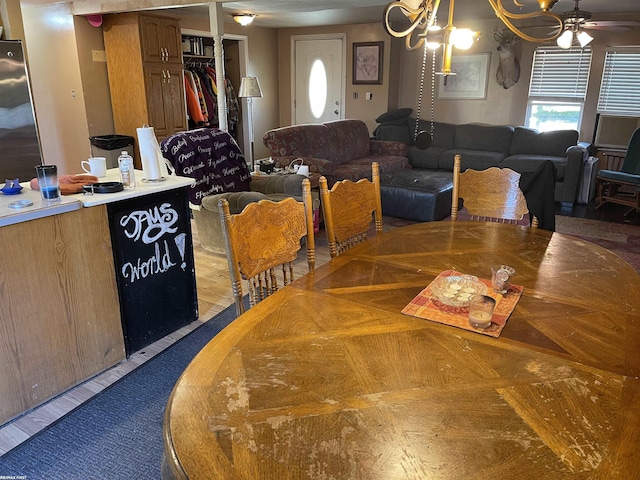 dining space with dark wood-type flooring and ceiling fan with notable chandelier