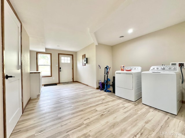 clothes washing area featuring light hardwood / wood-style floors and washer and clothes dryer