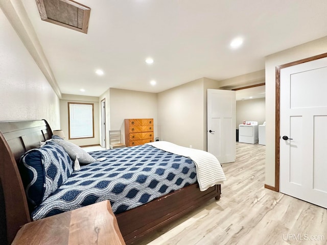 bedroom with separate washer and dryer and light hardwood / wood-style flooring