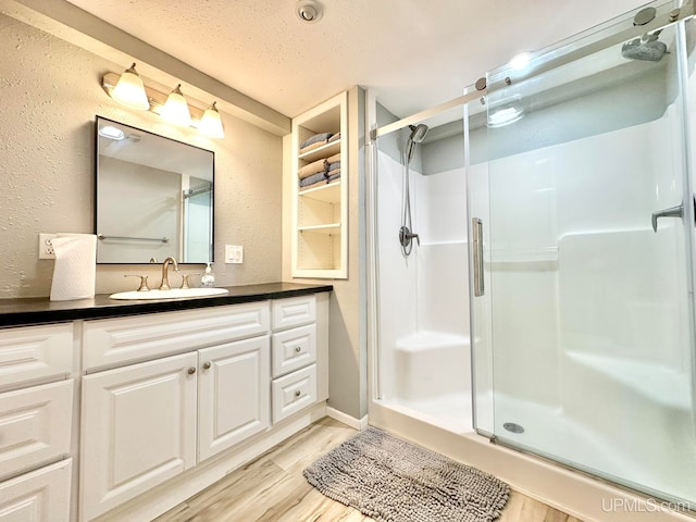 bathroom featuring vanity, a textured ceiling, wood-type flooring, and a shower with shower door