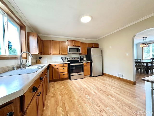 kitchen featuring light wood-type flooring, pendant lighting, stainless steel appliances, and a notable chandelier