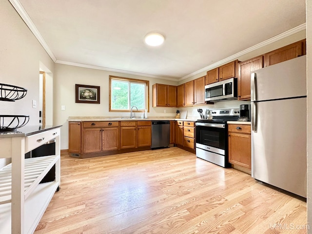 kitchen featuring ornamental molding, stainless steel appliances, sink, and light wood-type flooring