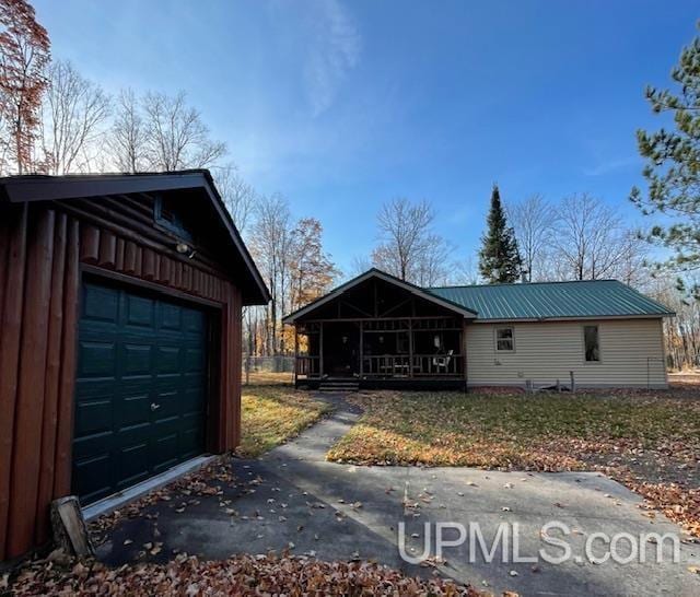 view of front of property featuring a garage, covered porch, driveway, and metal roof