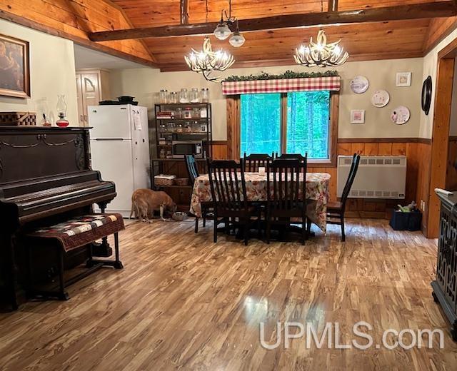 living room with lofted ceiling with beams, wood ceiling, wood-type flooring, and a wood stove