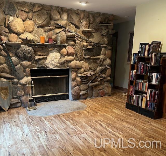 interior details with a stone fireplace and wood finished floors