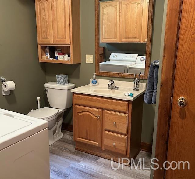 bathroom featuring washer and dryer, vanity, toilet, and wood finished floors