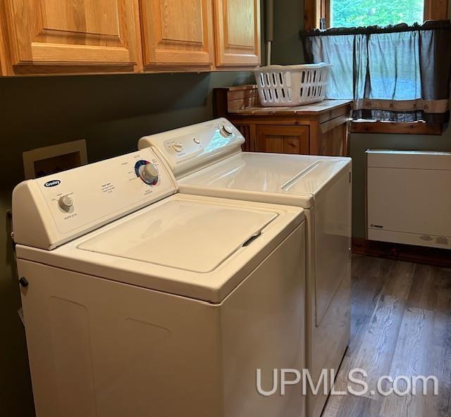 clothes washing area with cabinet space, washing machine and dryer, and dark wood-style floors