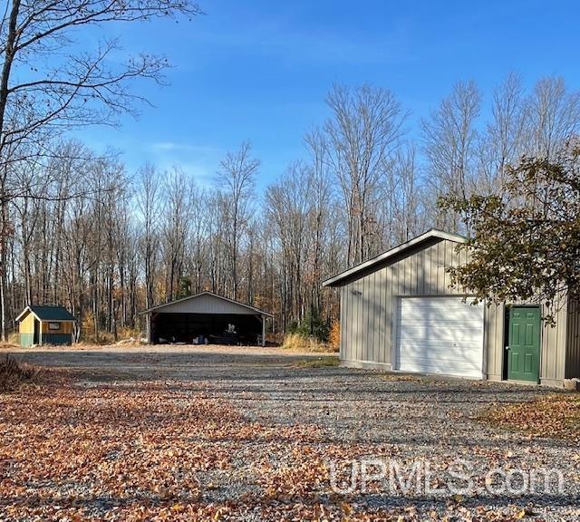 exterior space with driveway, a carport, and an outdoor structure