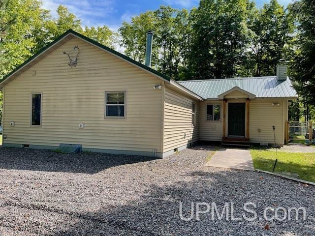 view of front of property with entry steps, metal roof, crawl space, and a chimney