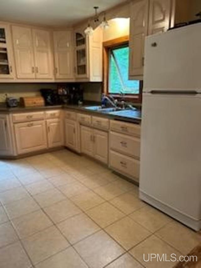 kitchen featuring white fridge, light tile patterned flooring, and sink