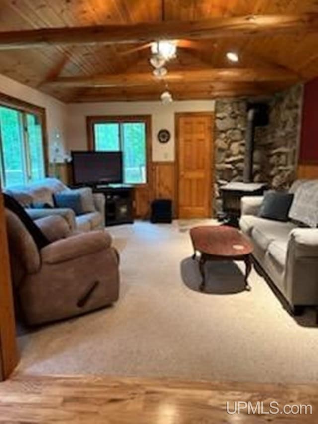 living room with wood ceiling, a wood stove, vaulted ceiling with beams, and hardwood / wood-style floors