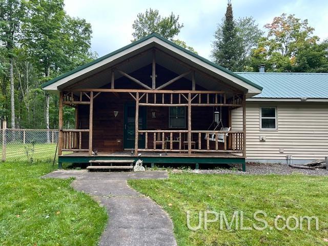 view of front of property with metal roof, a porch, a front lawn, and fence