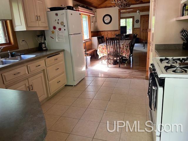 kitchen featuring light brown cabinets, white appliances, and light tile patterned floors