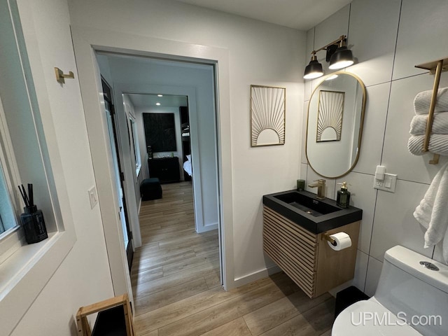 bathroom featuring toilet, vanity, baseboards, and wood finished floors