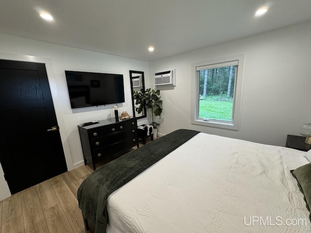 bedroom with a wall unit AC, recessed lighting, and wood finished floors