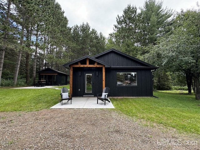 rear view of property featuring a patio area, board and batten siding, and a yard
