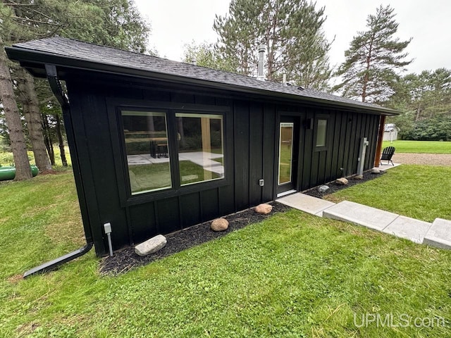 exterior space featuring a shingled roof, board and batten siding, and a yard