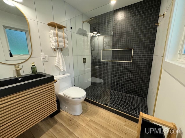 bathroom with tiled shower, vanity, toilet, and hardwood / wood-style flooring