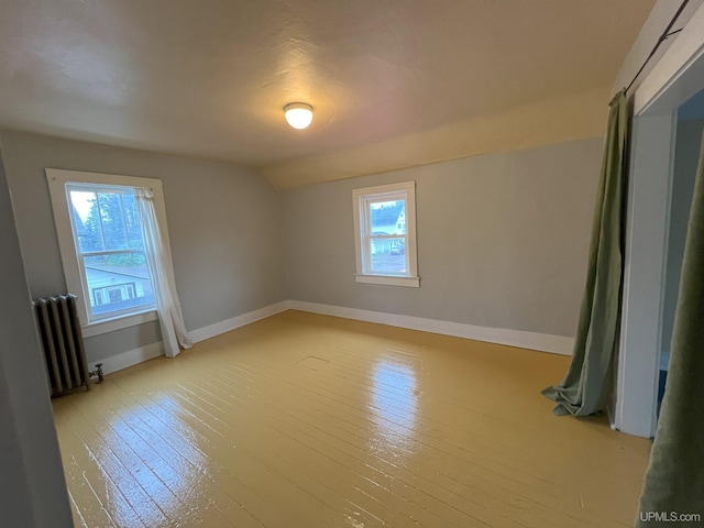 spare room featuring light hardwood / wood-style floors, a wealth of natural light, and radiator