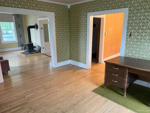 interior space featuring a wood stove, light hardwood / wood-style floors, and crown molding