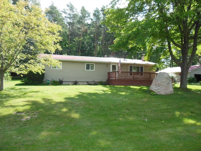 back of house featuring a deck, a lawn, and metal roof