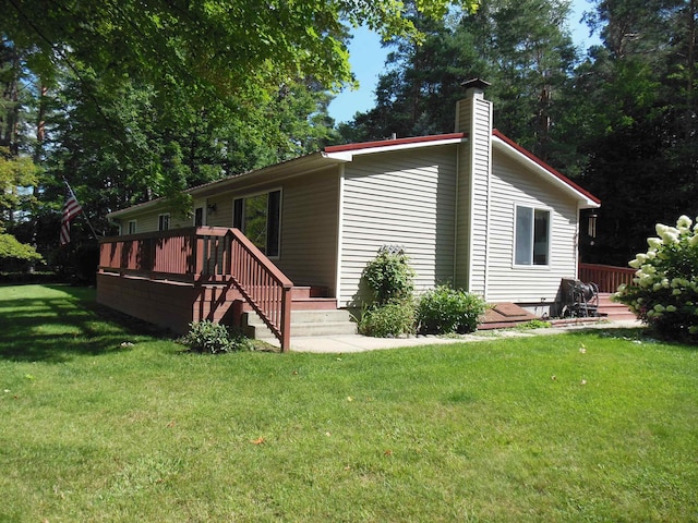 view of front of property featuring a front yard, a chimney, and a wooden deck