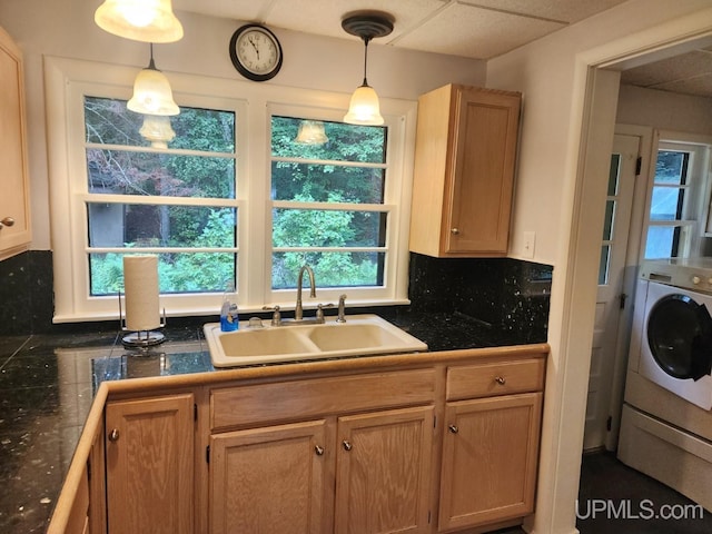 kitchen featuring tasteful backsplash, a paneled ceiling, sink, hanging light fixtures, and washer / clothes dryer