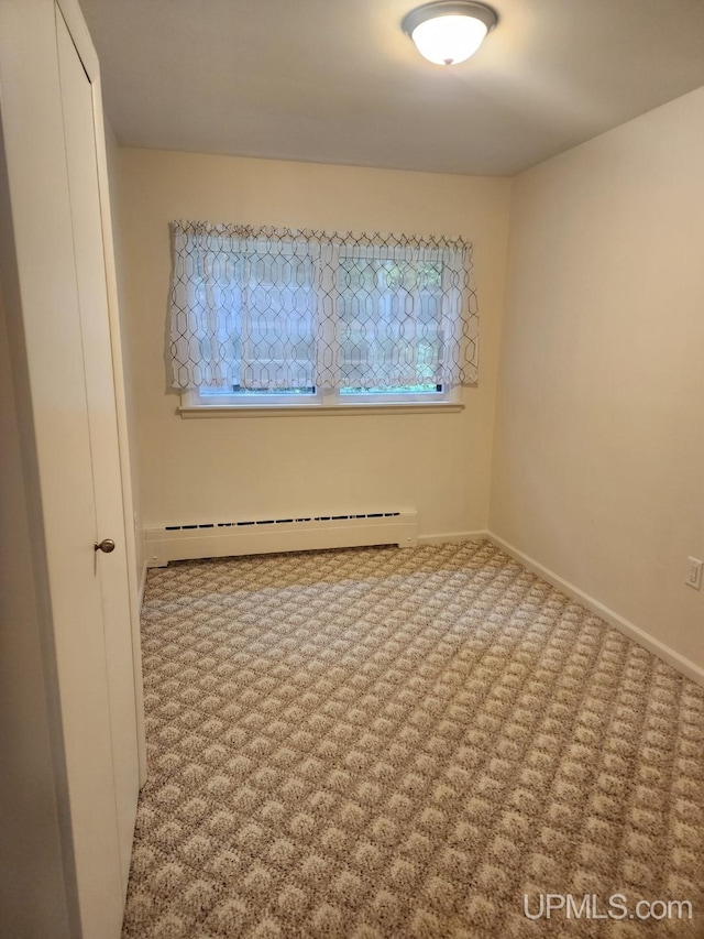 spare room featuring a baseboard heating unit and carpet flooring