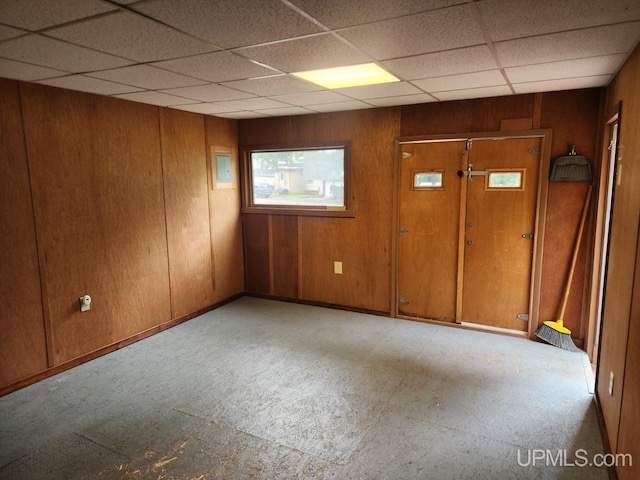 spare room with wooden walls and a drop ceiling