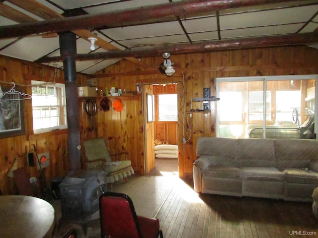 living room with a wealth of natural light, vaulted ceiling with beams, wooden walls, and hardwood / wood-style flooring