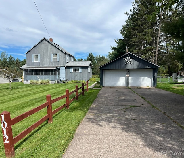 view of front of home featuring a front lawn, a garage, and an outdoor structure