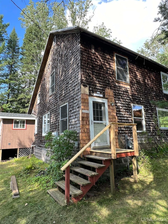 back of house with a storage shed and a yard