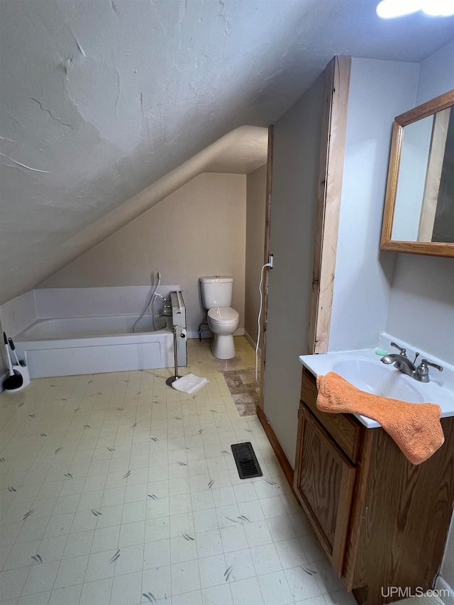 bathroom featuring vanity, toilet, a tub, and lofted ceiling