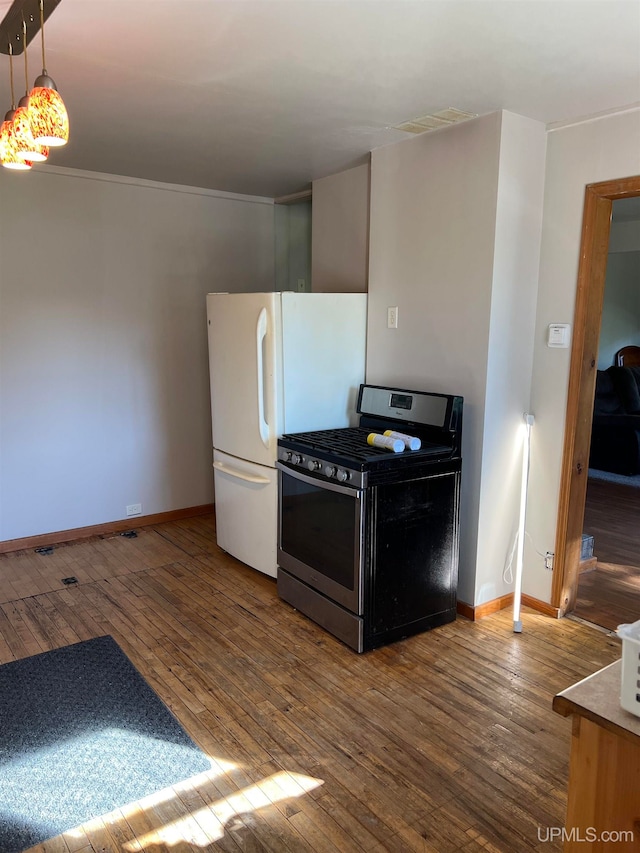 kitchen featuring white refrigerator, pendant lighting, hardwood / wood-style flooring, and stainless steel gas stove