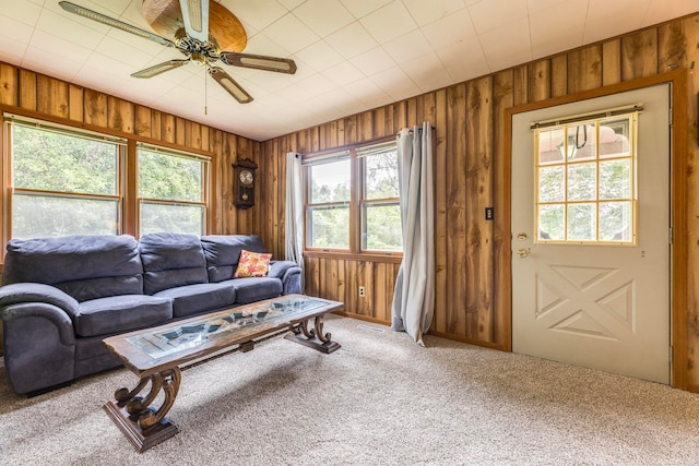 living room with carpet flooring, ceiling fan, and wooden walls