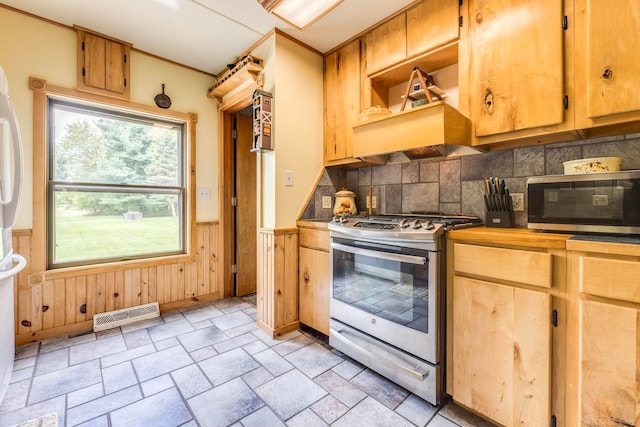 kitchen with backsplash, stainless steel appliances, wooden walls, and custom exhaust hood