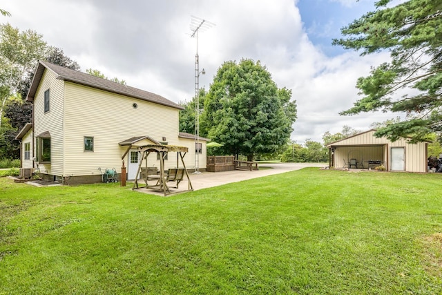 view of yard featuring an outbuilding, a garage, and a patio