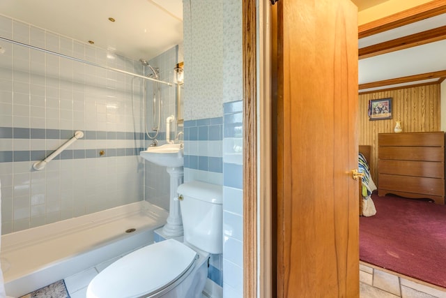 bathroom with toilet, tile patterned flooring, backsplash, tiled shower, and tile walls