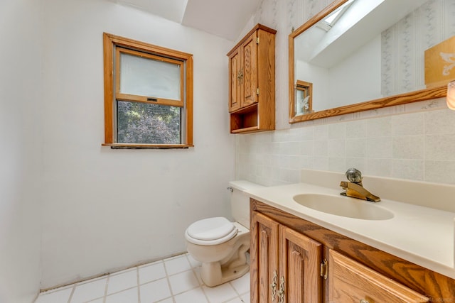 bathroom with a skylight, backsplash, tile patterned floors, toilet, and vanity