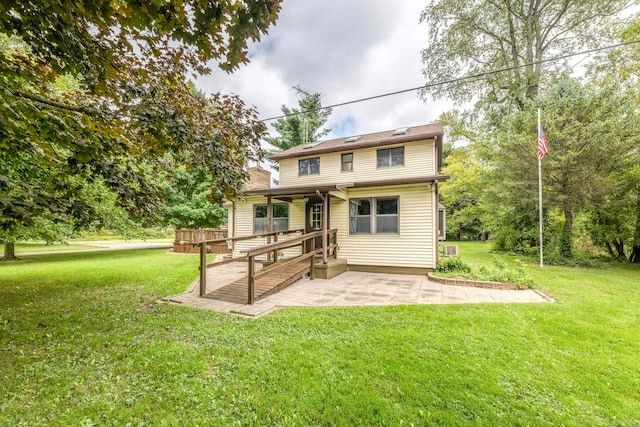 rear view of property featuring a patio area, a lawn, and a wooden deck