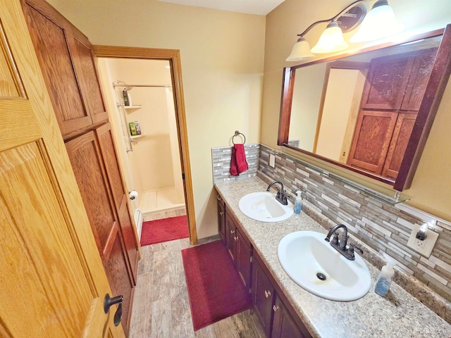 bathroom with a shower, backsplash, hardwood / wood-style flooring, and vanity