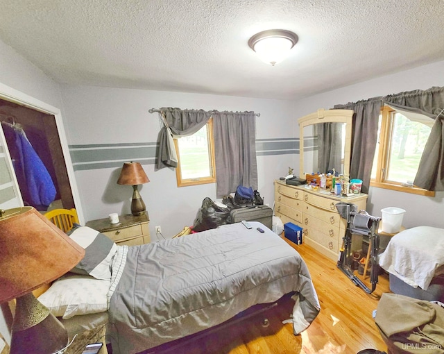 bedroom with a textured ceiling, light hardwood / wood-style flooring, and multiple windows