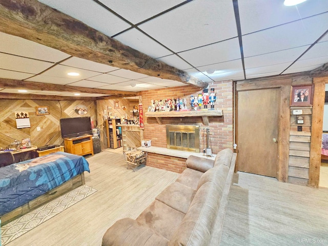 living room with a paneled ceiling, wooden walls, hardwood / wood-style flooring, and a fireplace