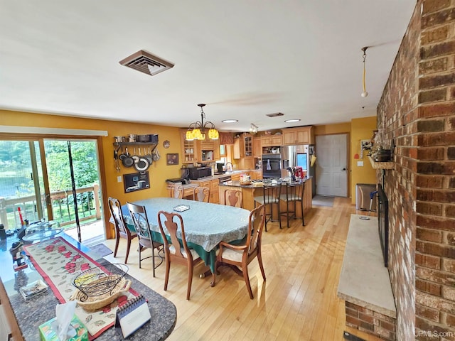 dining space with sink, a brick fireplace, and light hardwood / wood-style flooring