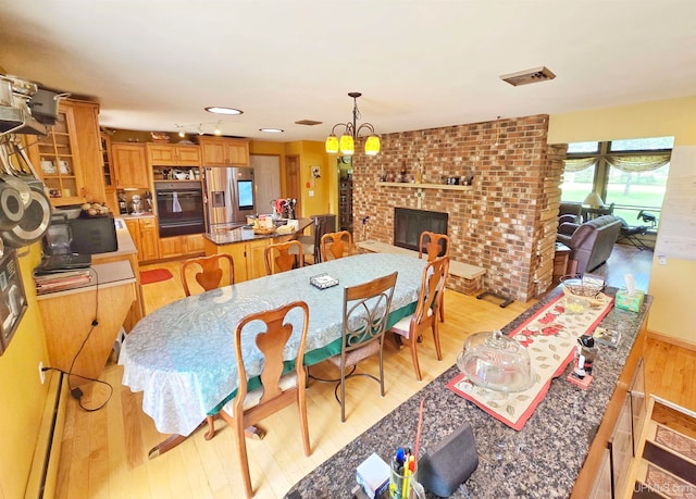 dining room featuring light hardwood / wood-style flooring and a brick fireplace