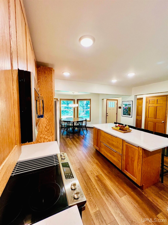 kitchen with a center island, light hardwood / wood-style flooring, decorative light fixtures, a breakfast bar area, and stove