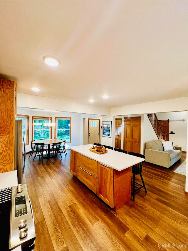 kitchen featuring a barn door, stainless steel refrigerator, wood-type flooring, a kitchen breakfast bar, and a kitchen island