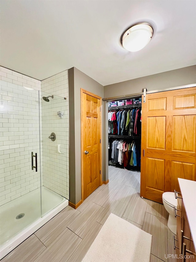 bathroom with a shower with shower door, toilet, and vanity