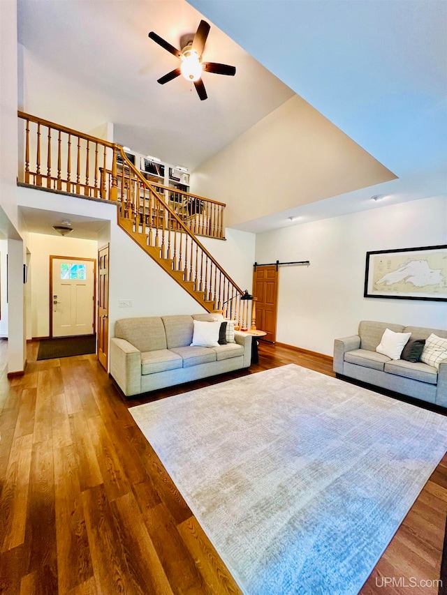 unfurnished living room featuring hardwood / wood-style flooring, ceiling fan, and a barn door